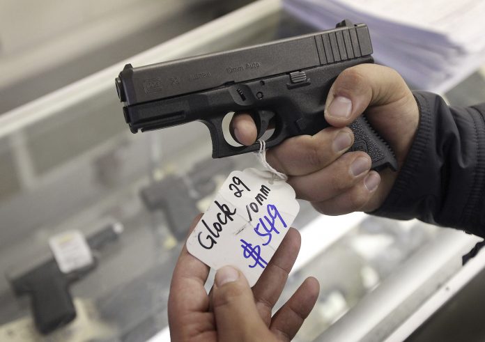 A customer looks over a Glock 29 10mm hand gun at the Guns-R-Us gun shop in Phoenix, Arizona